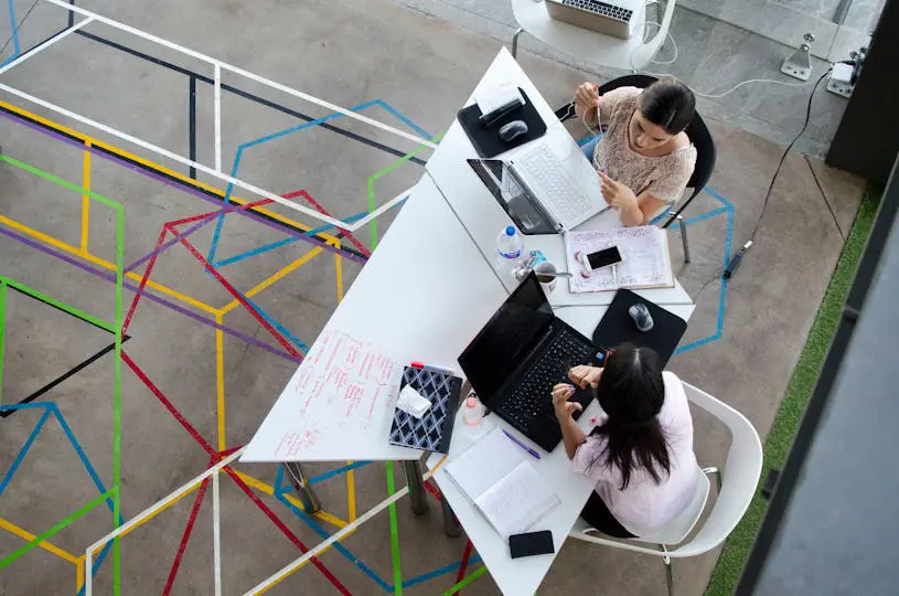 two-women-sitting-in-chairs-using-laptop-computers